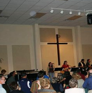 Congregation facing a cross, with circular light spots (angel orbs) near the ceiling