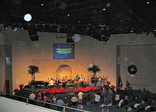 Church stage with projected text and red flowers, with circular light spots (angel orbs) in the photograph