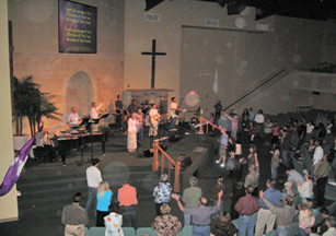 Worshippers standing before a stage cross, with circular light spots (angel orbs) in the photograph