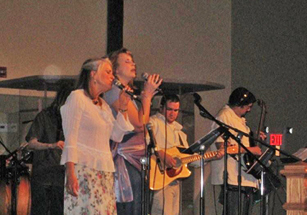 Woman singing into a microphone with musicians