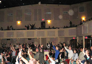 Congregation raising their hands, with circular light spots (angel orbs) in the photograph
