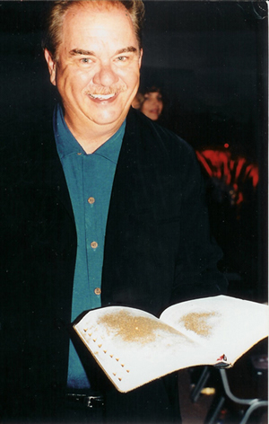 Jim Hart holding an open Bible with a gold-colored patch on its pages